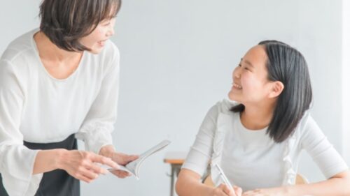 夏休みに家庭教師と一緒に勉強する小学生